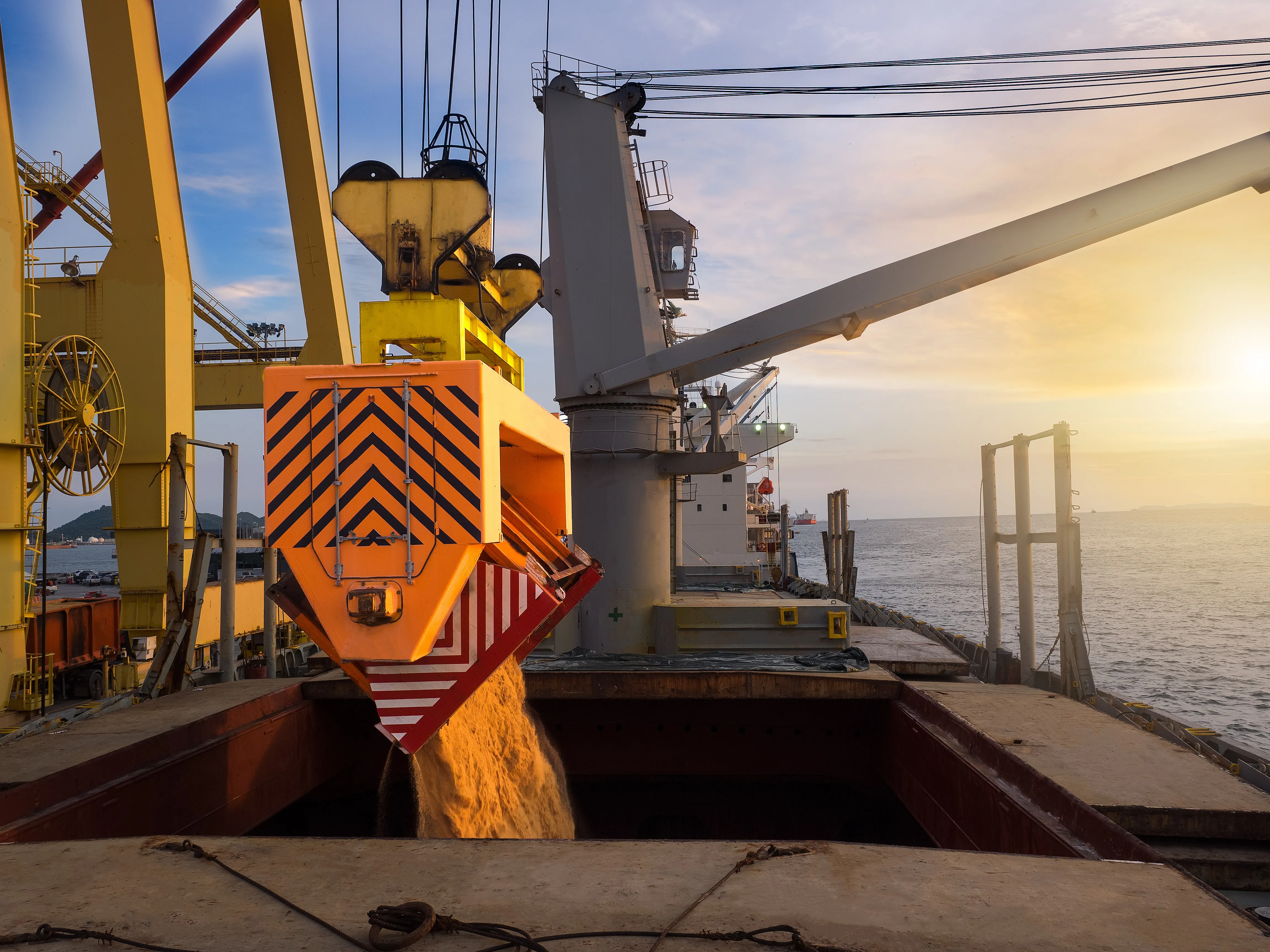 Carregamento de açúcar em navio graneleiro ao pôr do sol